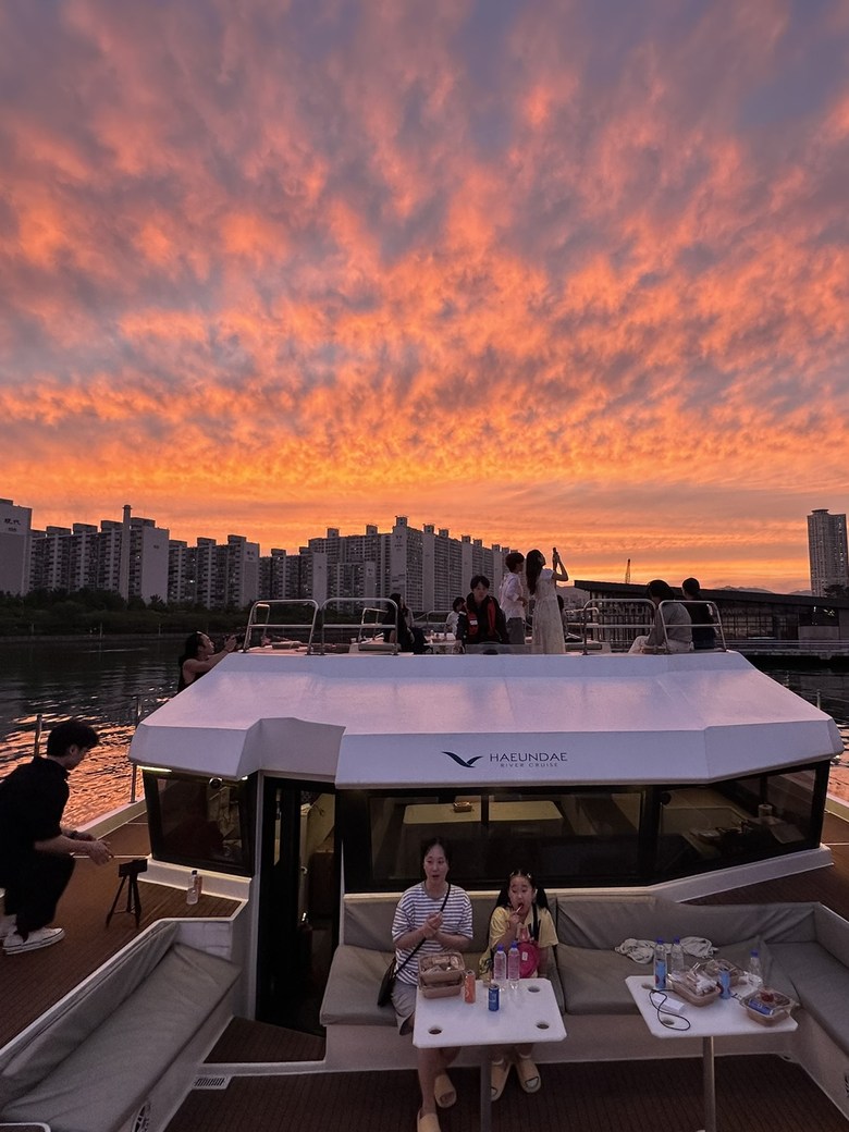 Guests seated on deck under a red sunset