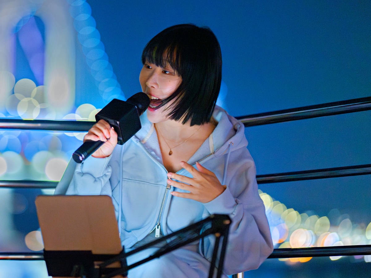 A busker singing at the bow against the night view of Gwangan Bridge