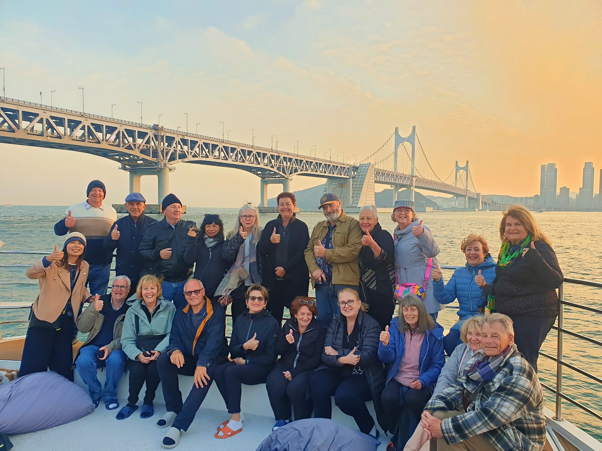 A private tour group seated together on deck under Gwangan Bridge