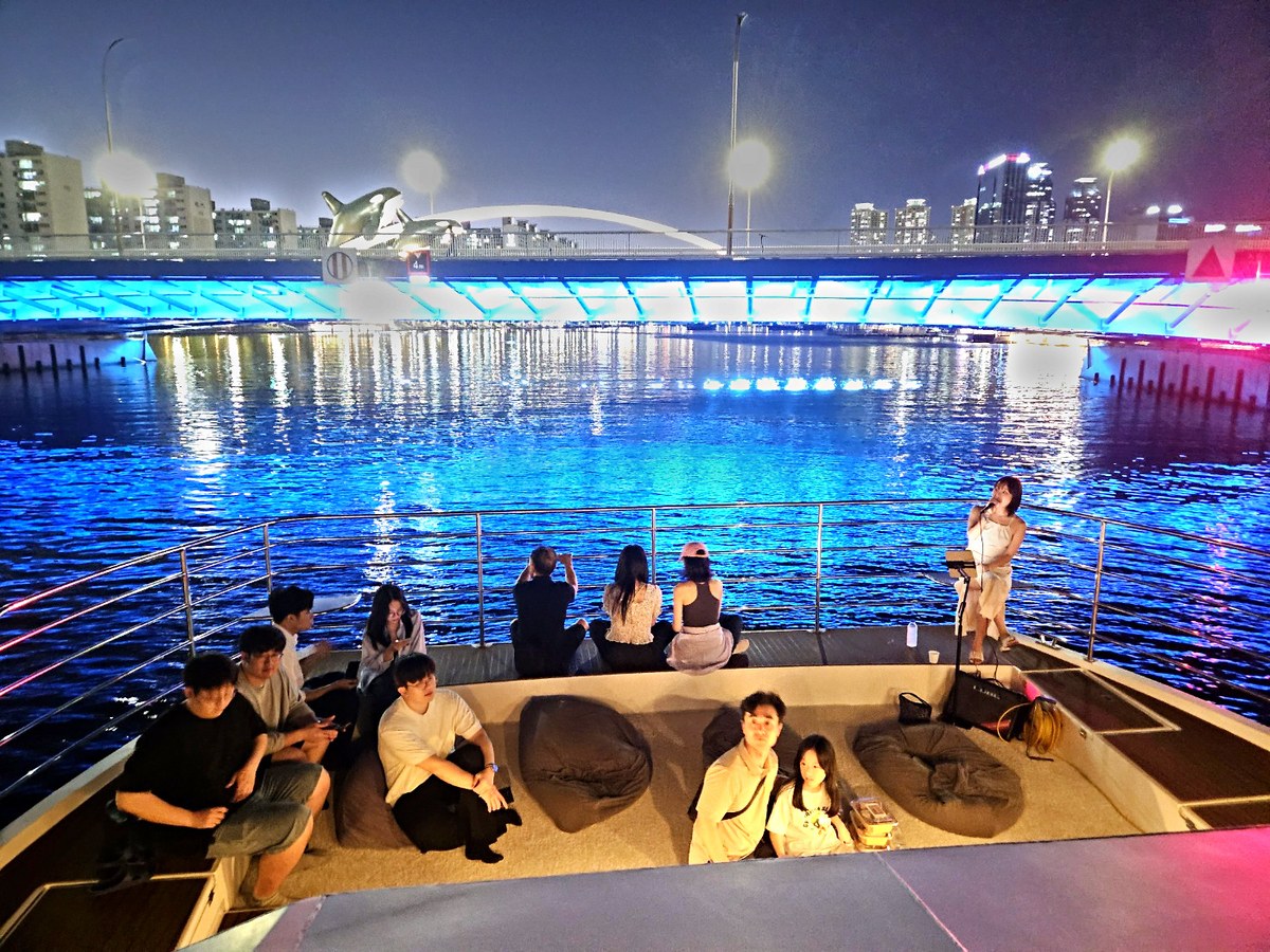 A group on the bow deck over the night sea during the drone show