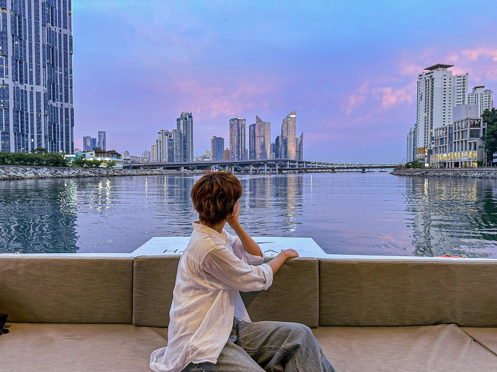 A passenger being photographed on deck at sunset