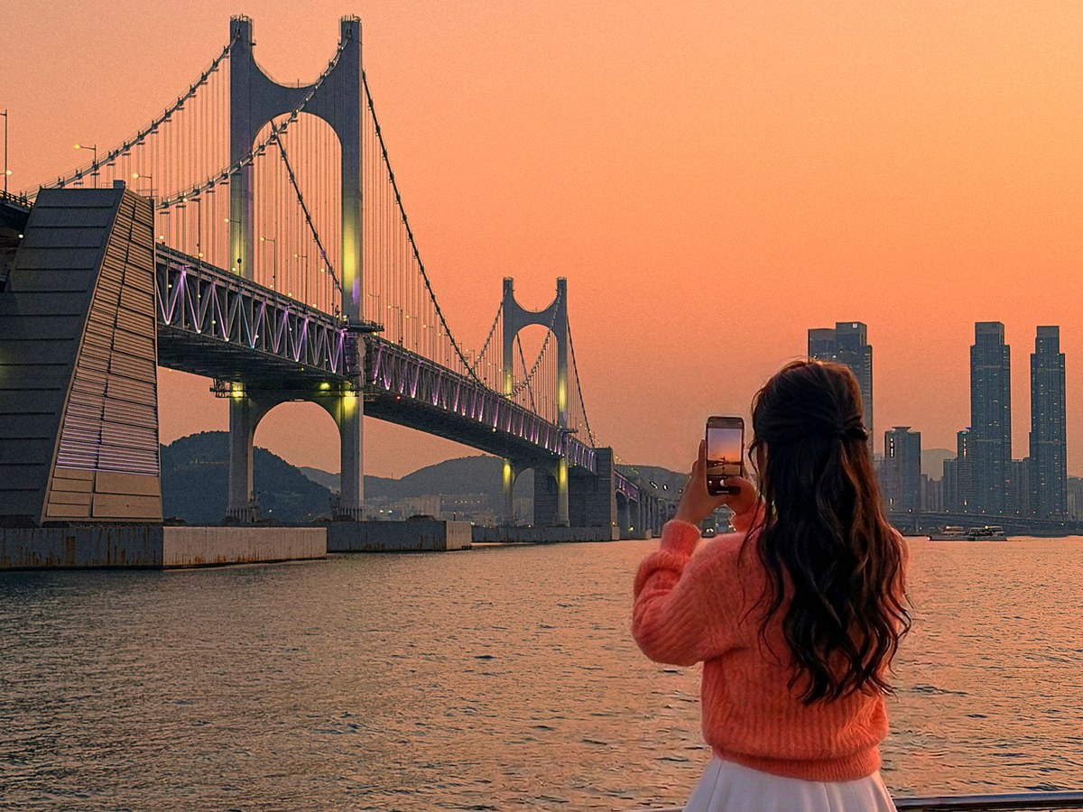 A guest photographing the golden sunset and Gwangan Bridge