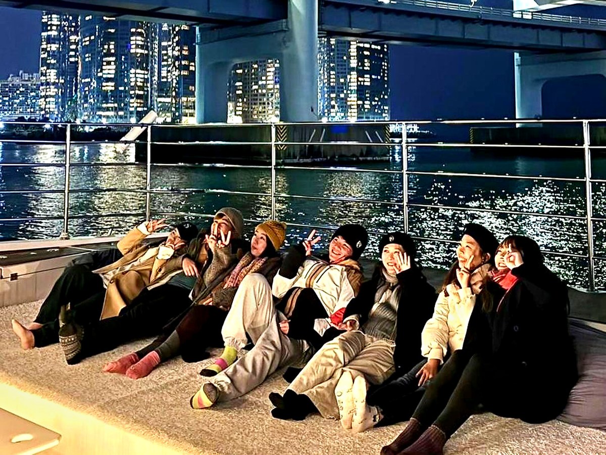 Guests seated on deck in front of Gwangan Bridge lit up at night