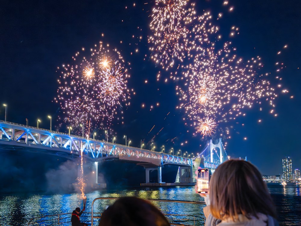 A passenger on the yacht watching fireworks burst above Gwangan Bridge