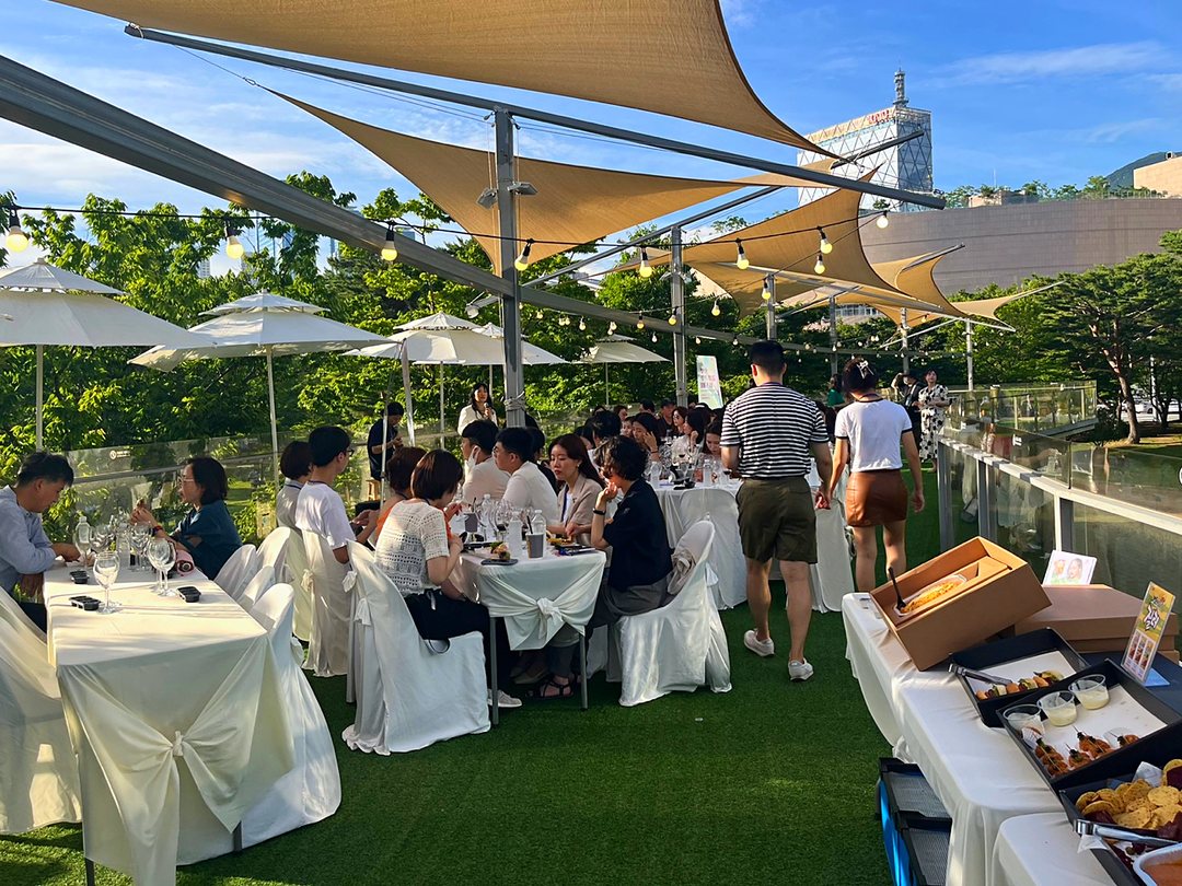 Group guests gathered at round tables under the sunshades